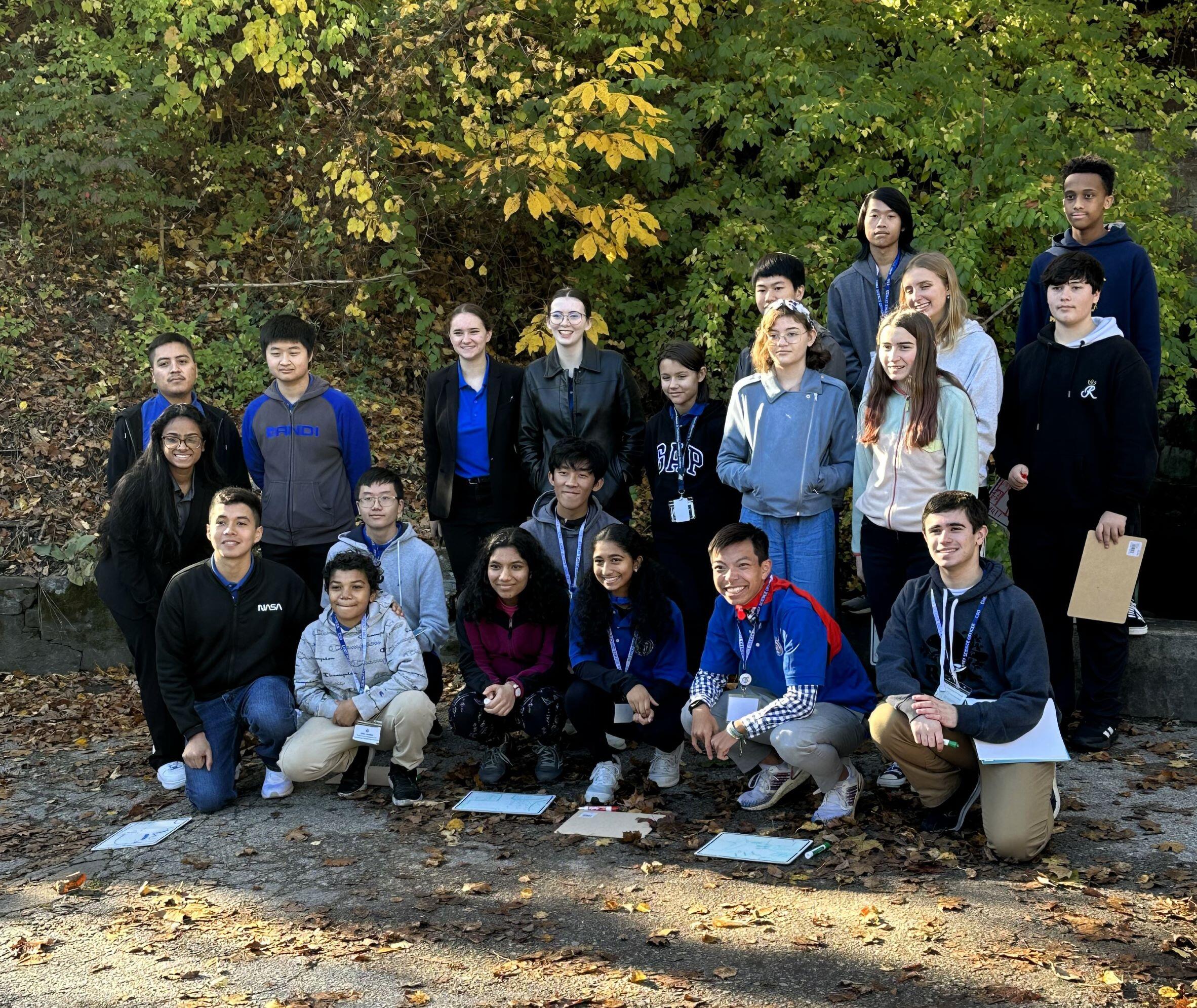Class of students on field trip standing for a group photo in front of fall foliage