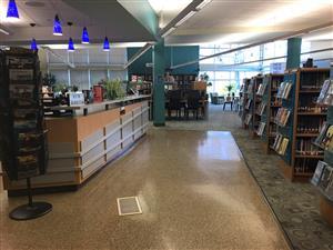 photo of the middle school library. It shows the book shelves on the right and check out area on the left. There is an isle down the middle