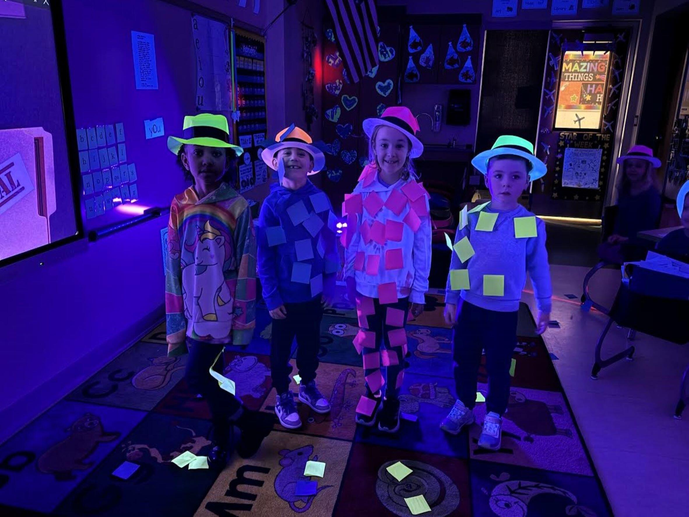 Four students wearing post it notes under a black light