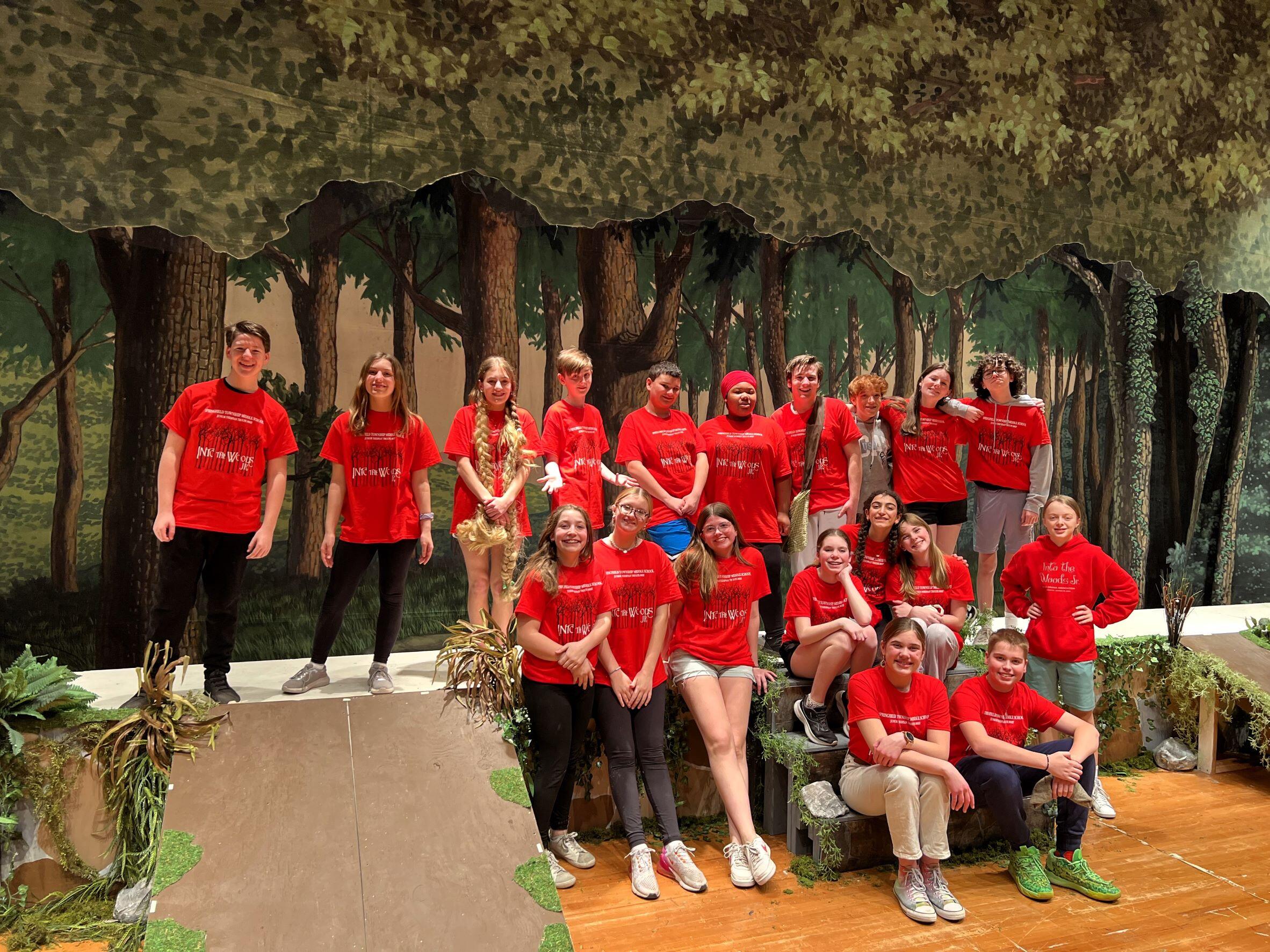 cast of school play, grouped for a photo. All students are wearing red shirts with the play's title, "Into the Woods"
